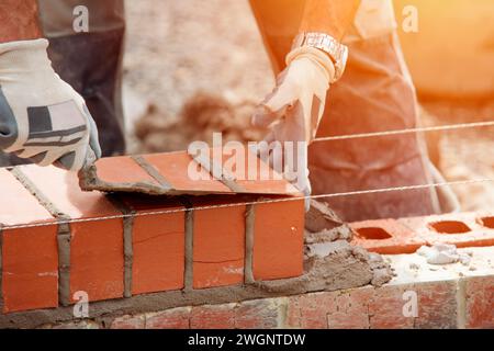 Industrial bricklayer laying bricks on cement mix on construction site close-up Stock Photo