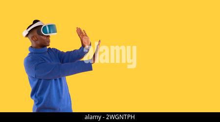 African American female in modern VR headset   exploring virtual reality universe on yellow background Stock Photo
