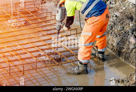 Builder using electric braker fot breaking concrete from the top of pile to fit reinforcement cage on top of it Stock Photo