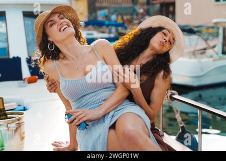 Two women share a laugh on a yacht, basking in pure joy and friendship. Stock Photo