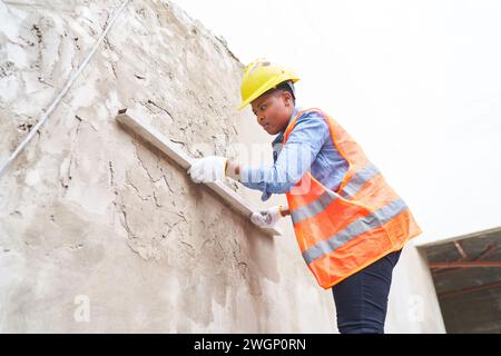 Female labor plastering on wall with cement Stock Photo