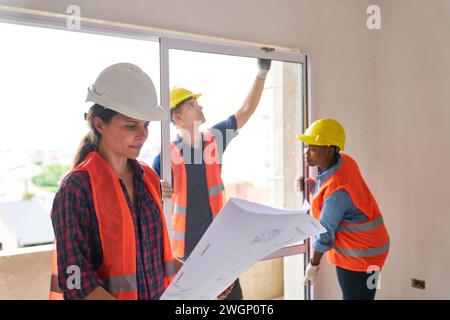 Architect examining blueprint near carpenters at site Stock Photo