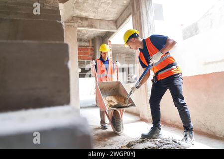 Young male and female masons mixing cement Stock Photo