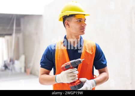Smiling male construction labor holding power tool Stock Photo