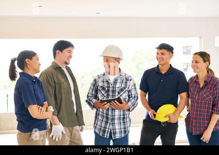 Smiling contractor holding tablet PC discussing with team Stock Photo