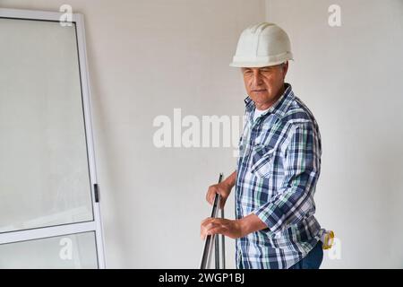 Senior male contractor standing with window frame Stock Photo