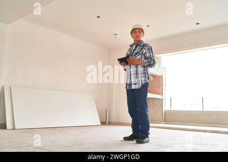 Architect wearing hardhat standing with tablet PC Stock Photo