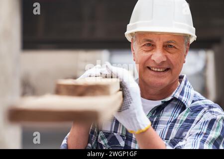 Senior male worker with planks on shoulder Stock Photo