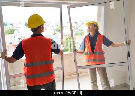 Carpenters installing window frames in house Stock Photo