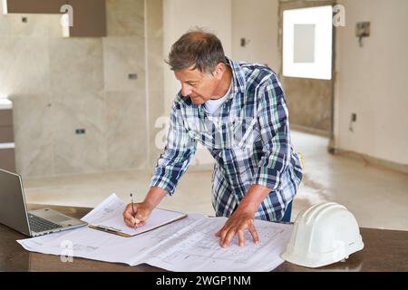 Senior architect writing on clipboard over design Stock Photo