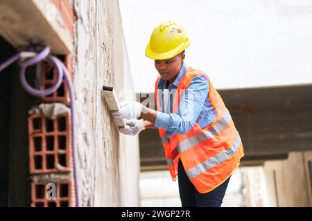 Female labor plastering on wall with mortar Stock Photo