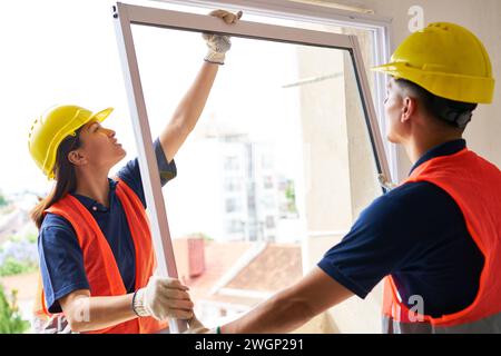 Two carpenters installing window in house Stock Photo