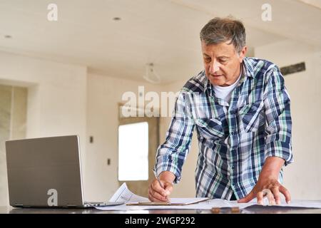 Senior architect writing on clipboard over blueprint Stock Photo