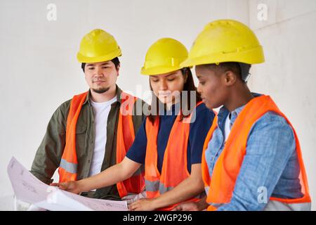 Diverse team discussing while examining blueprint Stock Photo