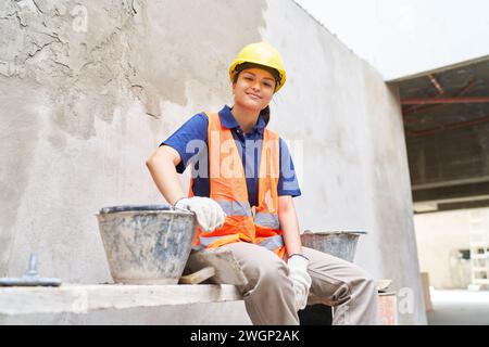 Confident female bricklayer amidst buckets Stock Photo