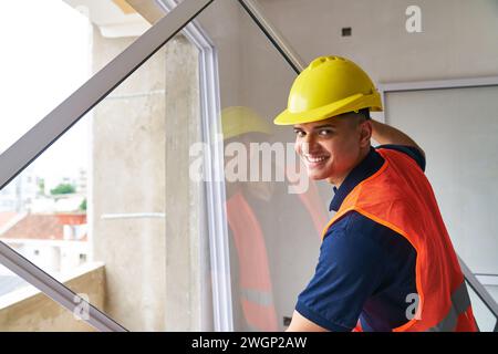 Smiling young male carpenter installing window frame Stock Photo