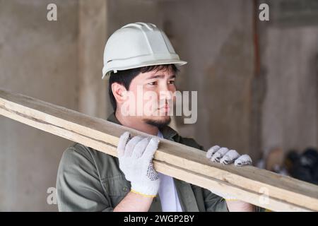 Male carpenter carrying planks on shoulder Stock Photo