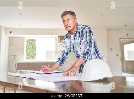 Senior architect with blueprint at desk Stock Photo