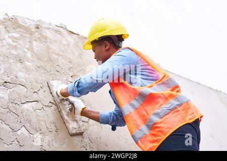 Female labor plastering on wall with cement Stock Photo