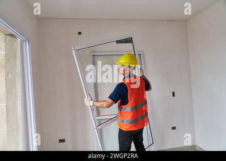 Young male carpenter installing window frame Stock Photo