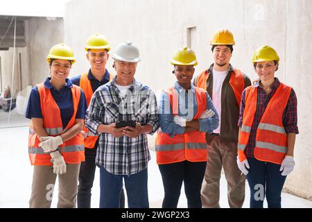 Smiling male builder with team wearing hardhats Stock Photo