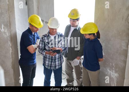 Senior contractor sharing tablet PC with workers Stock Photo