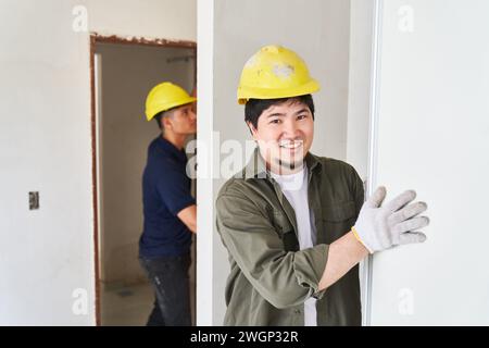 Smiling male worker fitting door Stock Photo