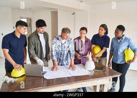 Tean of construction workers and architect meeting over blueprint discussing work Stock Photo