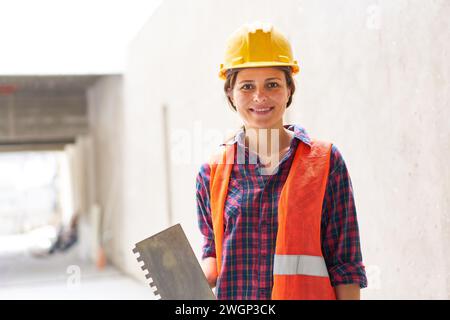 Confident female construction worker holding trowel Stock Photo