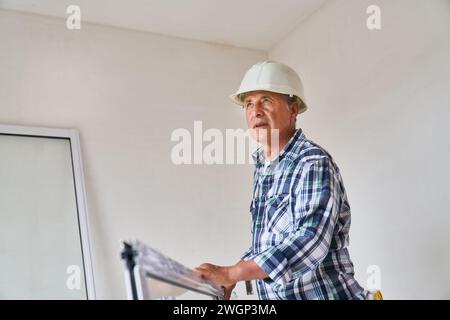 Senior male carpenter standing with window frame Stock Photo