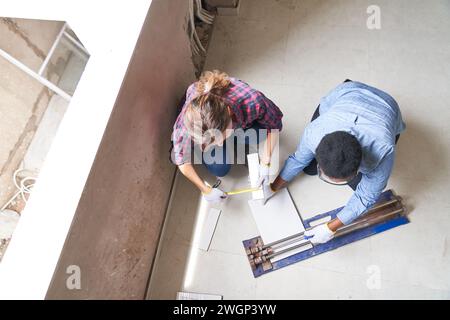 Female coworkers measuring and cutting plank Stock Photo