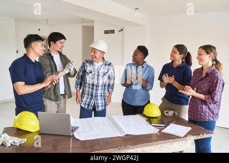 Team of workers applauding architect in meeting Stock Photo
