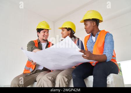 Diverse team discussing while examining blueprint Stock Photo