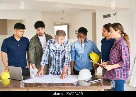 Team of workers and architect discussing over blueprint Stock Photo