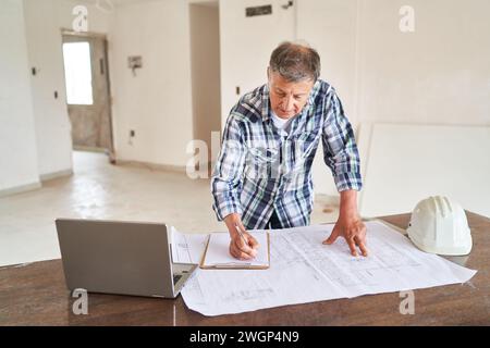 Senior architect writing on clipboard over blueprint Stock Photo