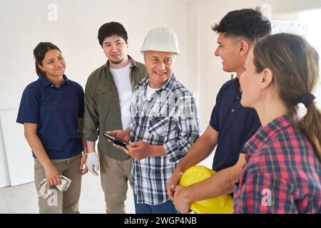 Senior contractor holding tablet PC discussing with team Stock Photo