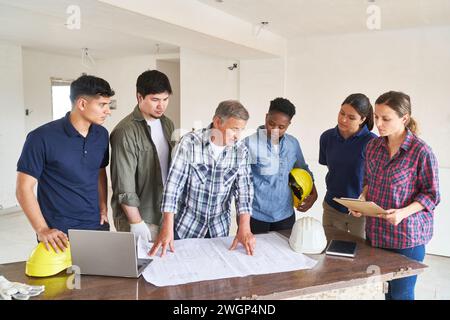 Team of workers and architect discussing over blueprint Stock Photo