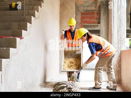 Young male and female masons mixing cement Stock Photo