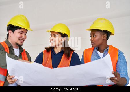 Smiling diverse team discussing while examining blueprint Stock Photo