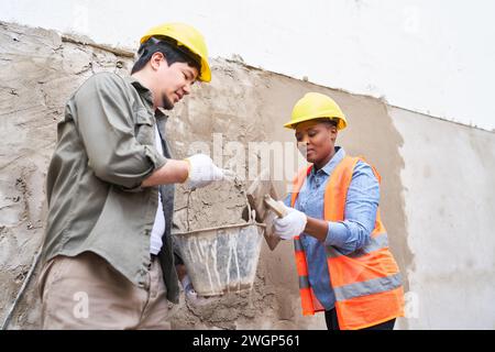 Male and female bricklayers plastering wall with mortar Stock Photo