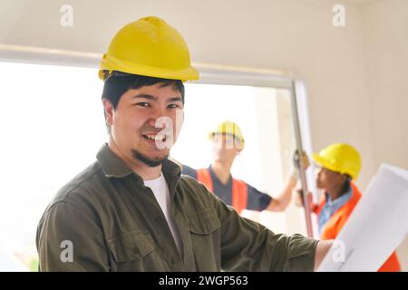Architect with blueprint near carpenters at site Stock Photo