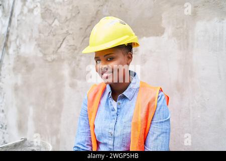 Smiling young female mason wearing hardhat Stock Photo