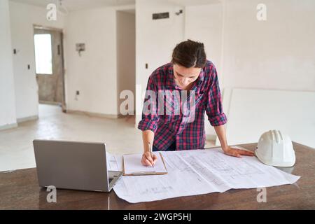 Young architect writing on clipboard over blueprint Stock Photo
