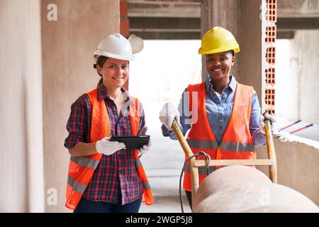 Smiling contractor with tablet PC standing by mason Stock Photo