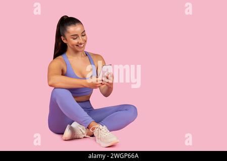 Young woman in activewear using phone post-workout Stock Photo