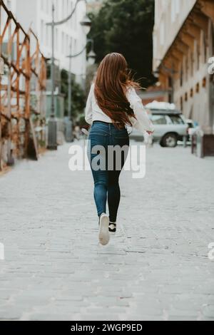 Rear view woman running away outdoors Stock Photo