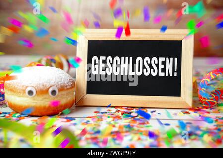 6 February 2024: Closed, writing on a carnival sign with doughnuts, streamers and confetti PHOTOMONTAGE *** Geschlossen, Schrift auf einem Schild zu Fasching mit Krapfen, Luftschlangen und Konfetti FOTOMONTAGE Stock Photo