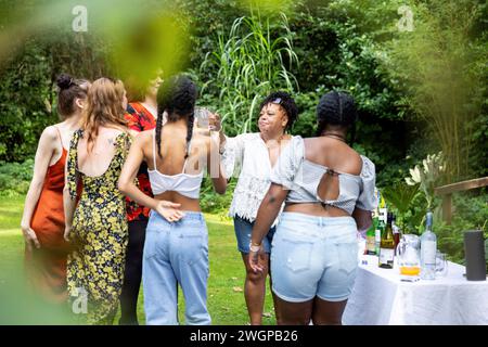 Mixed group of female friends / family at a summer garden BBQ party, laughing and having fun Stock Photo