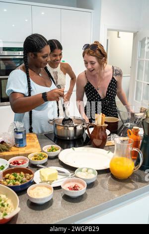 A mixed group of female friends preparing party food in a modern kitchen Stock Photo