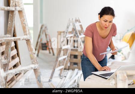 Woman construction manager checking project documentation, using laptop Stock Photo